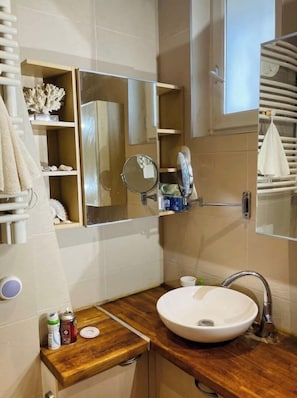 Une salle de bain avec un meuble-lavabo en bois, un lavabo blanc et un miroir.