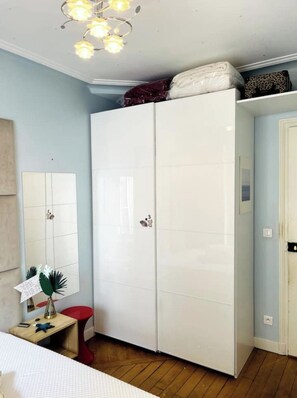 Une chambre avec une armoire, un bureau avec une lampe et un lit.