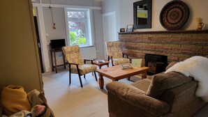 A living room with a fireplace, two armchairs, a sofa, a coffee table, and a television.