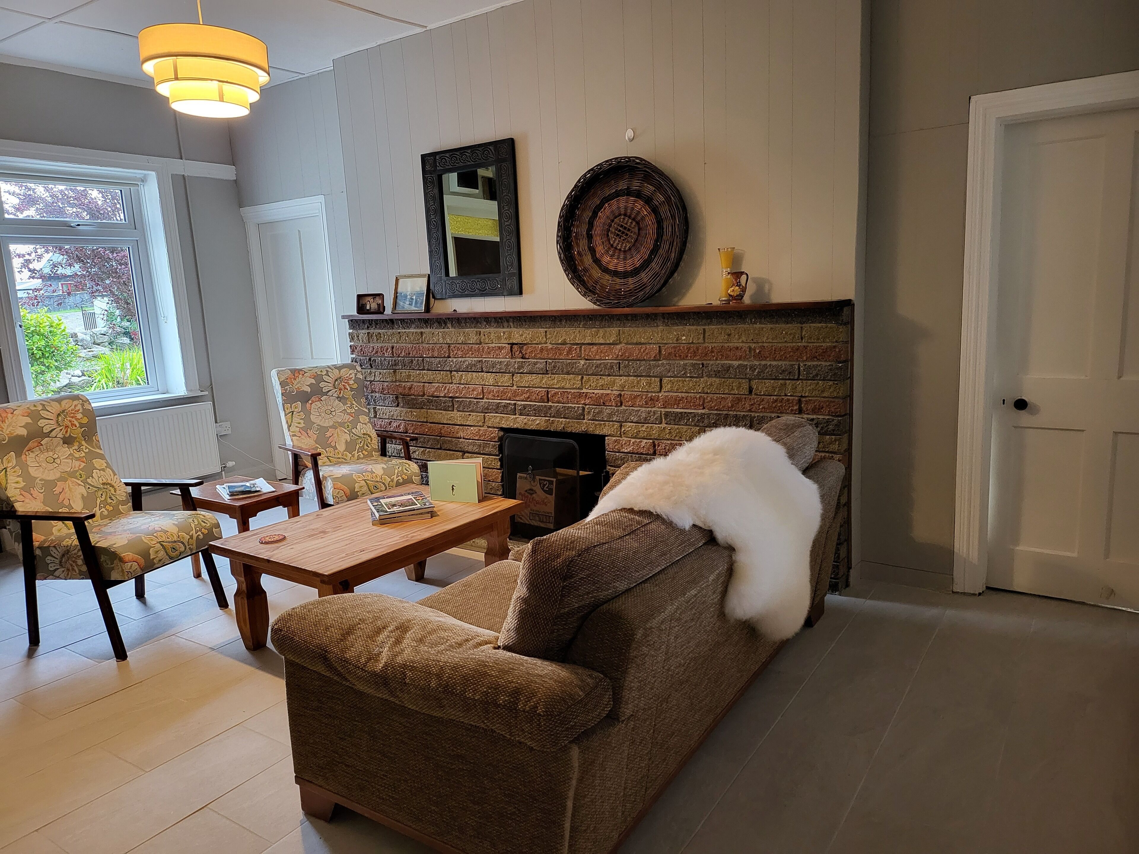 A living room with a brick fireplace, a sofa, a chair, and a wooden coffee table.