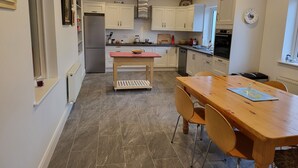 A modern kitchen with white cabinets, a central island, and a dining table with chairs.