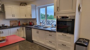 A modern kitchen with white cabinets, a built-in oven, and a window providing a view of the outdoors.
