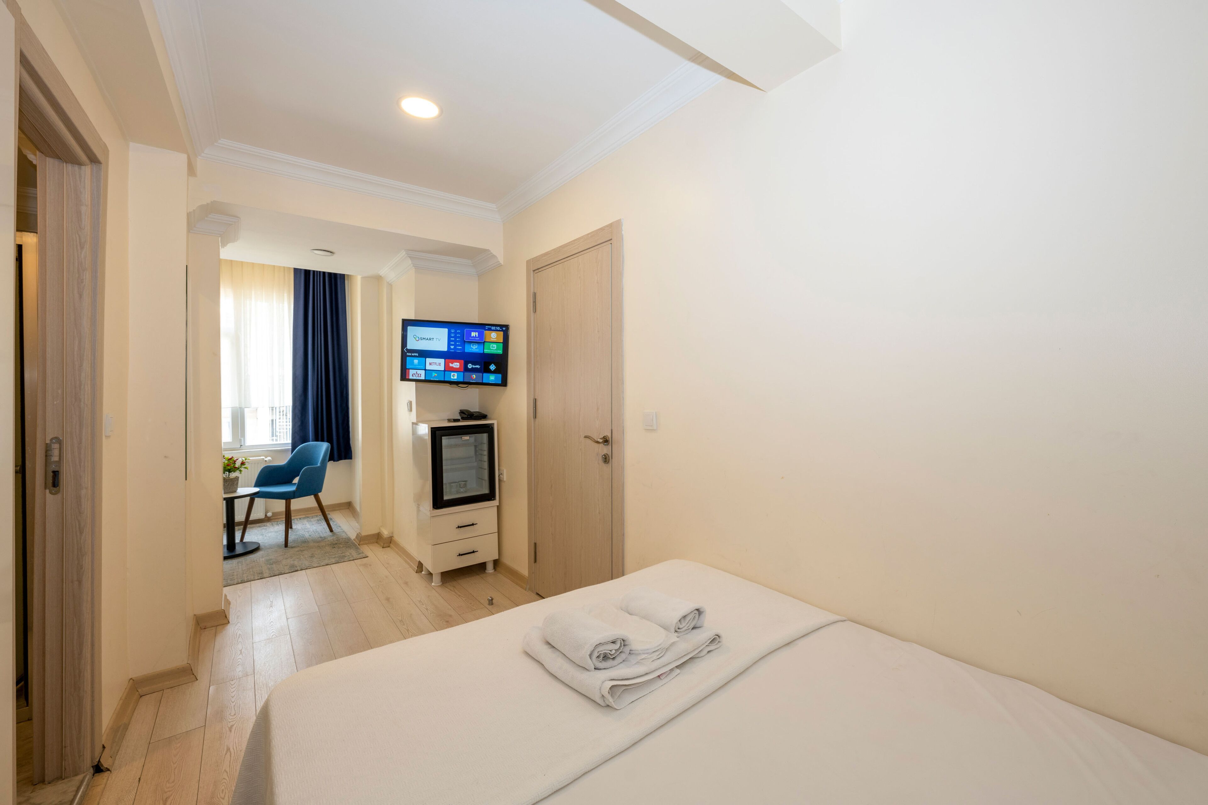 A hotel room with a bed, a TV, a desk, and a chair.