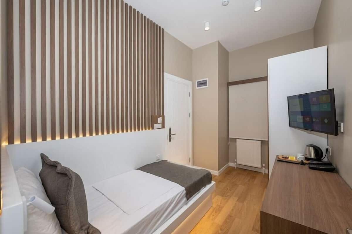 A modern room with a bed, a desk, a TV, and a wardrobe.