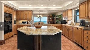 Una cocina amplia con una isla grande, armarios de madera y vista al océano.