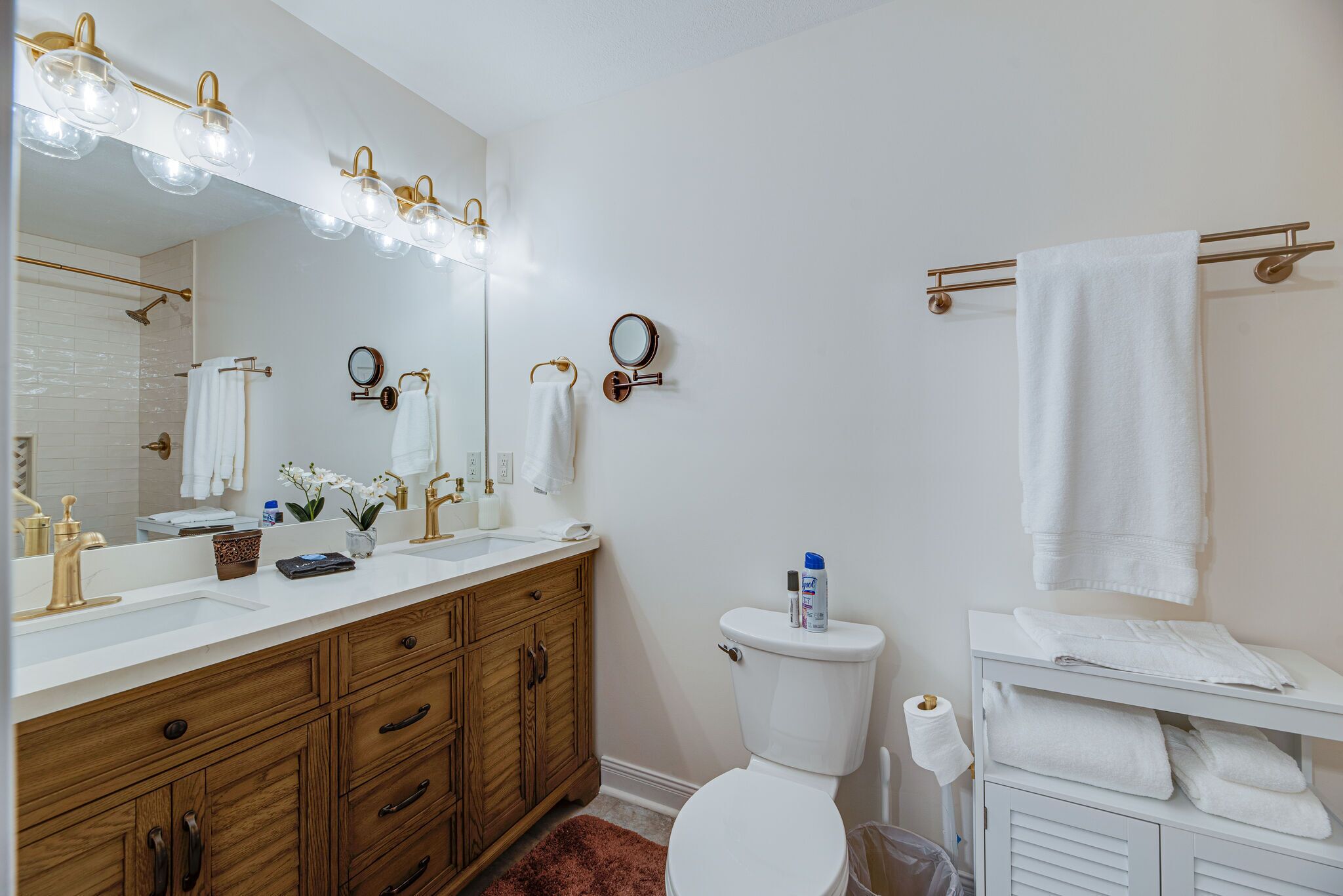 A bathroom with a white sink, wooden vanity, a toilet, and a towel rack.