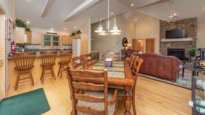 Un vaste espace de vie comprenant une table à manger, des chaises en bois, un canapé et une cheminée.