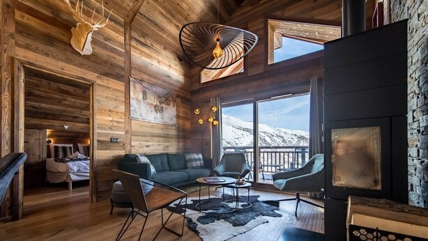 A cozy cabin interior with a wooden interior, a fireplace, a sofa, and a dining area.