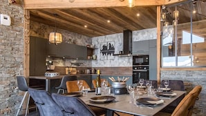 A modern dining area with a wooden ceiling, stone walls, and a large table set for six.