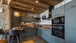 A modern kitchen with a stone wall, wooden ceiling, and a blue countertop.