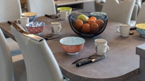 A modern dining area with a round table, white chairs, and a bowl of fruit. - Olvera 402 - New apartment on the slopes (VALMEINIER)