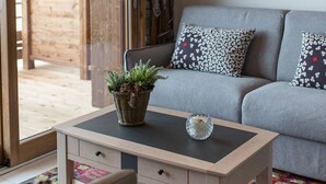 A cozy living room with a grey sofa, patterned cushions, a wooden coffee table with a plant and candle, and a colorful rug. - Olvera 402 - New apartment on the slopes (VALMEINIER)