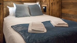 Een bed met een blauwe deken en twee opgevouwen handdoeken.