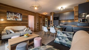 Een gezellige woonkamer met een bank, salontafel en een eethoek met stoelen en een tafel gedekt voor een maaltijd.