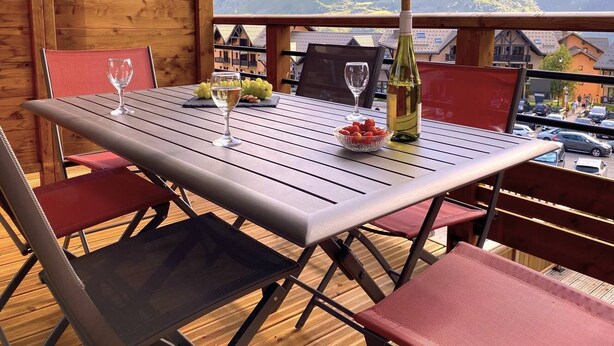 Een houten terras met een gedekte tafel, met uitzicht op een bergachtig landschap.