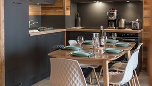 Een moderne keuken met donkere kastjes, houten details en een eethoek met een tafel voor vier personen.