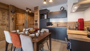 A modern kitchen with a dining area, wooden accents, and a red coffee machine. - Olvera 203 - New apartment at the foot of the slopes (VALMEINIER)