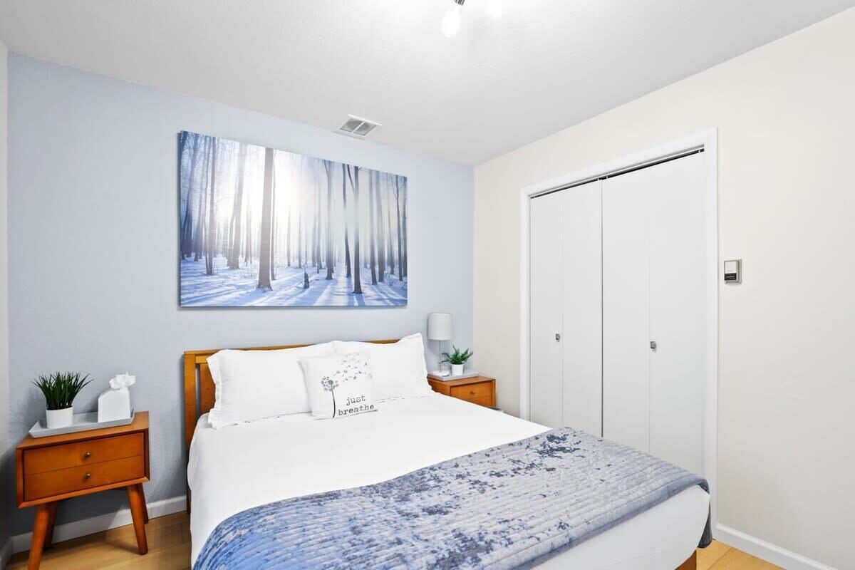 Un dormitorio con cama, mesita de noche, armario y un cuadro colgado en la pared.