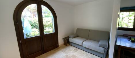Una habitación con un gran arco, un sofá de tonos claros y una pequeña mesa con un tazón.