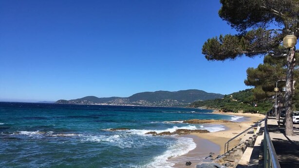 A coastal walkway with a rocky barrier, a clear blue sea, and distant hills. - The little House in Gigaro (La Croix-Valmer)