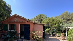 A small, rustic building with a tiled roof, a blue door, and a gravel driveway. - The little House in Gigaro (La Croix-Valmer)