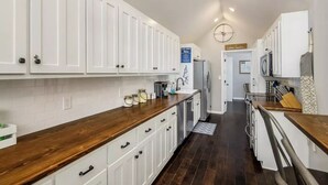 Cozinha moderna com armários brancos, bancadas de madeira e uma ilha central.