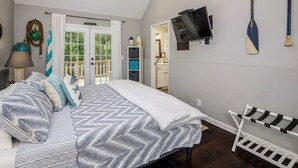 Quarto com cama, televisão fixada na parede e suporte com pranchas.