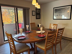 Un coin repas avec une table ronde, des chaises en bois et des sets de table rouges.