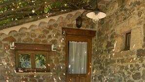 A stone building with a wooden door, a window, and a table with chairs. - Typical Cévenol Mazet with magnificent view (Saint jean du gard)