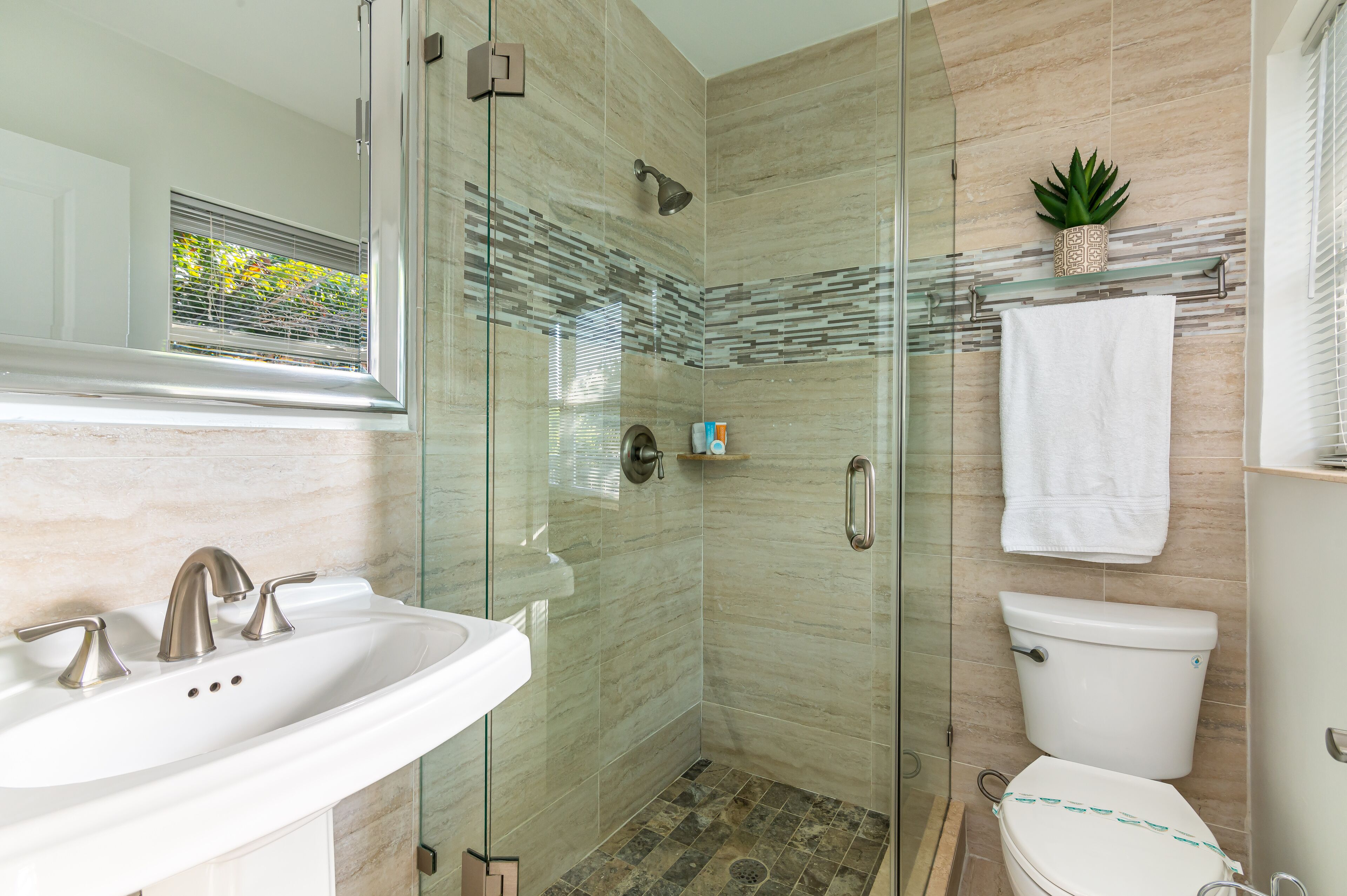 A modern bathroom with a glass-enclosed shower, a white sink, and a toilet.