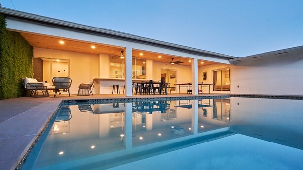 A modern outdoor pool area with a clear pool, seating, and a covered patio. - Villa Athena • Basketball Court | Heated Pool (Miami)