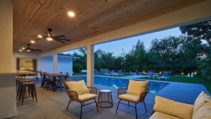 A covered outdoor area with a pool, wicker furniture, and a ceiling fan. - Villa Athena • Basketball Court | Heated Pool (Miami)