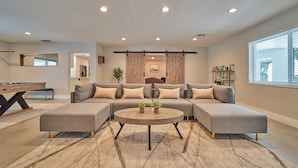 A modern living room with a sectional sofa, a round coffee table, and a pool table. - Villa Athena • Basketball Court | Heated Pool (Miami)