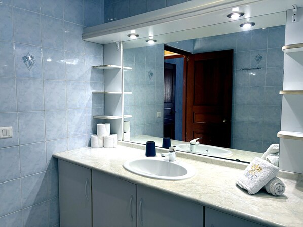 A bathroom with a white sink, mirror, and blue tiles. - TAHITI - Fare Vairai Pool (Faa´a)