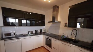 A modern kitchen with white cabinets, a black countertop, a microwave, a coffee maker, and a sink. - Casa La Vista - Relax & Unwind by Villas Now (Playa Blanca)