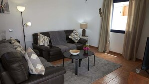A living room with a sofa, a coffee table, a lamp, and a TV. - Casa La Vista - Relax & Unwind by Villas Now (Playa Blanca)