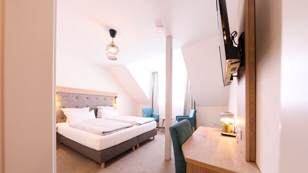 A modern hotel room with a large bed, a desk, and a chair. - 247 selfcheckin Schmiedestrasse (Leer)