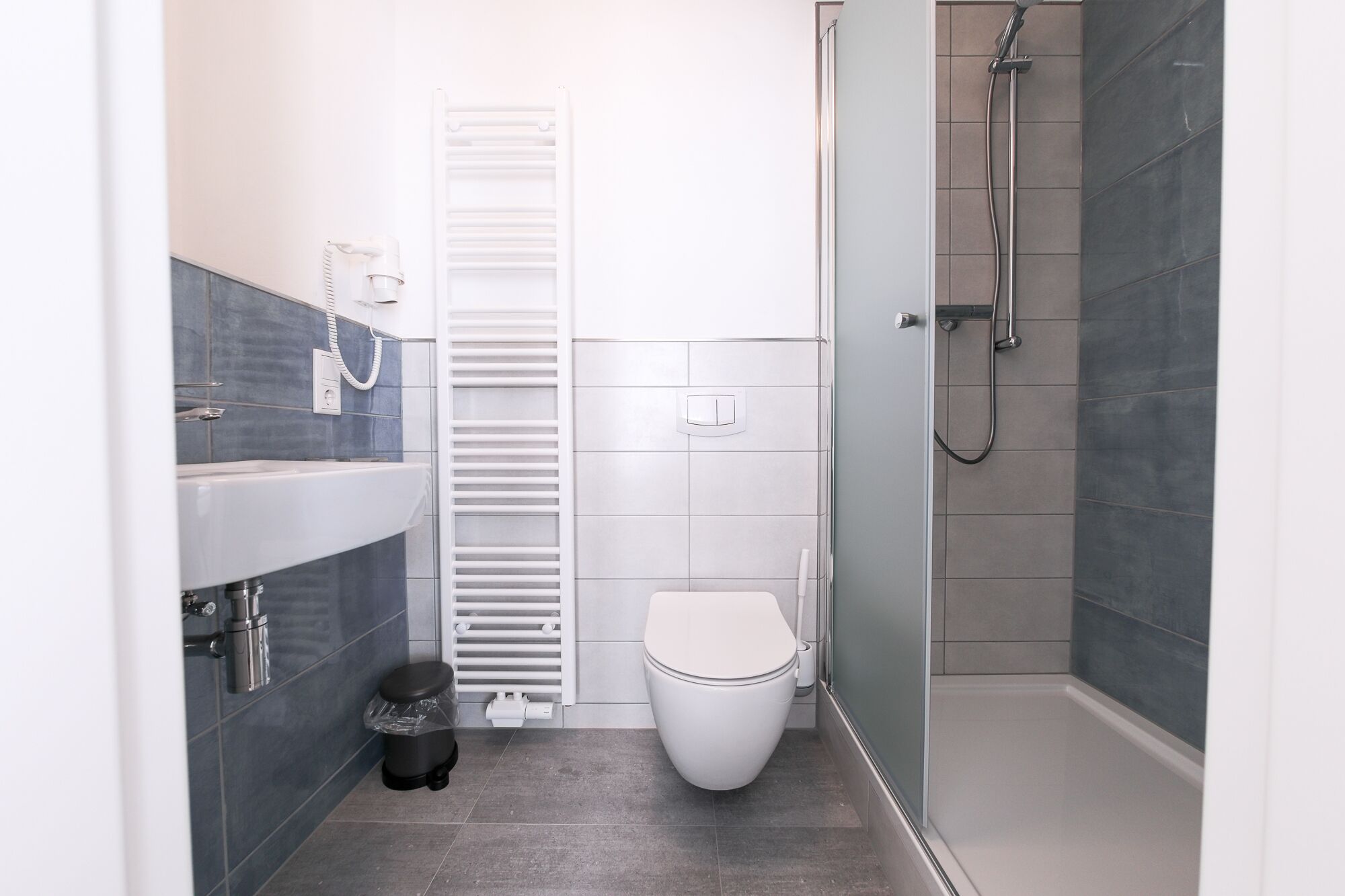 Een moderne badkamer met toilet, hygiëneschuimer en douche.
