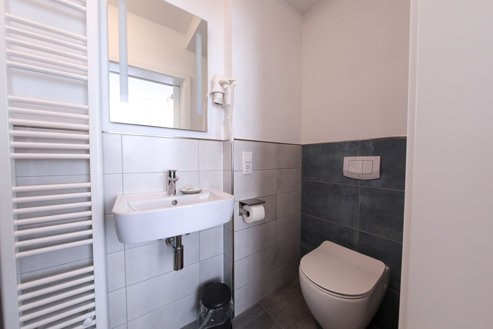 A modern bathroom with a white sink, a toilet, and a mirror.