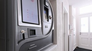 A wall-mounted security kiosk with a keypad and a screen, located in a hallway with white walls and a carpeted floor. - 247 selfcheckin Schmiedestrasse (Leer)