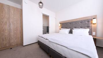 Una habitación de hotel con una cama grande, un armario, un espejo y una lámpara en el techo.