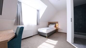 A modern, well-lit bedroom with a skylight, a bed, a desk, and a chair.
