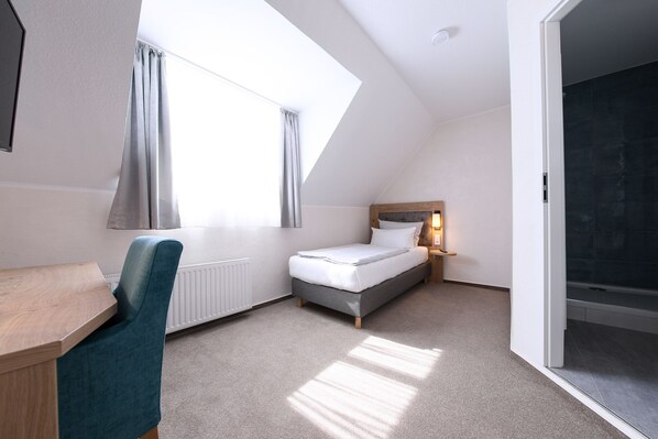 Un dormitorio moderno y luminoso con tragaluz, cama, escritorio y silla.