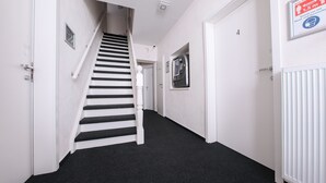 A narrow hallway with a black carpet, white walls, and a white door with a number. - 247 selfcheckin Schmiedestrasse (Leer)
