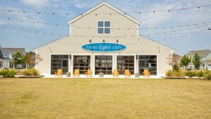 Een gebouw met een bord waarop ‘beau coast club’ staat, en buiten zitplaatsen met stoelen.
