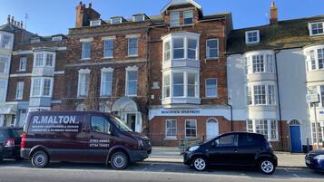 A building with a bay window, a sign for 'R. Malton Building Maintenance & Repairs', and a 'Beachview Apartment' sign.