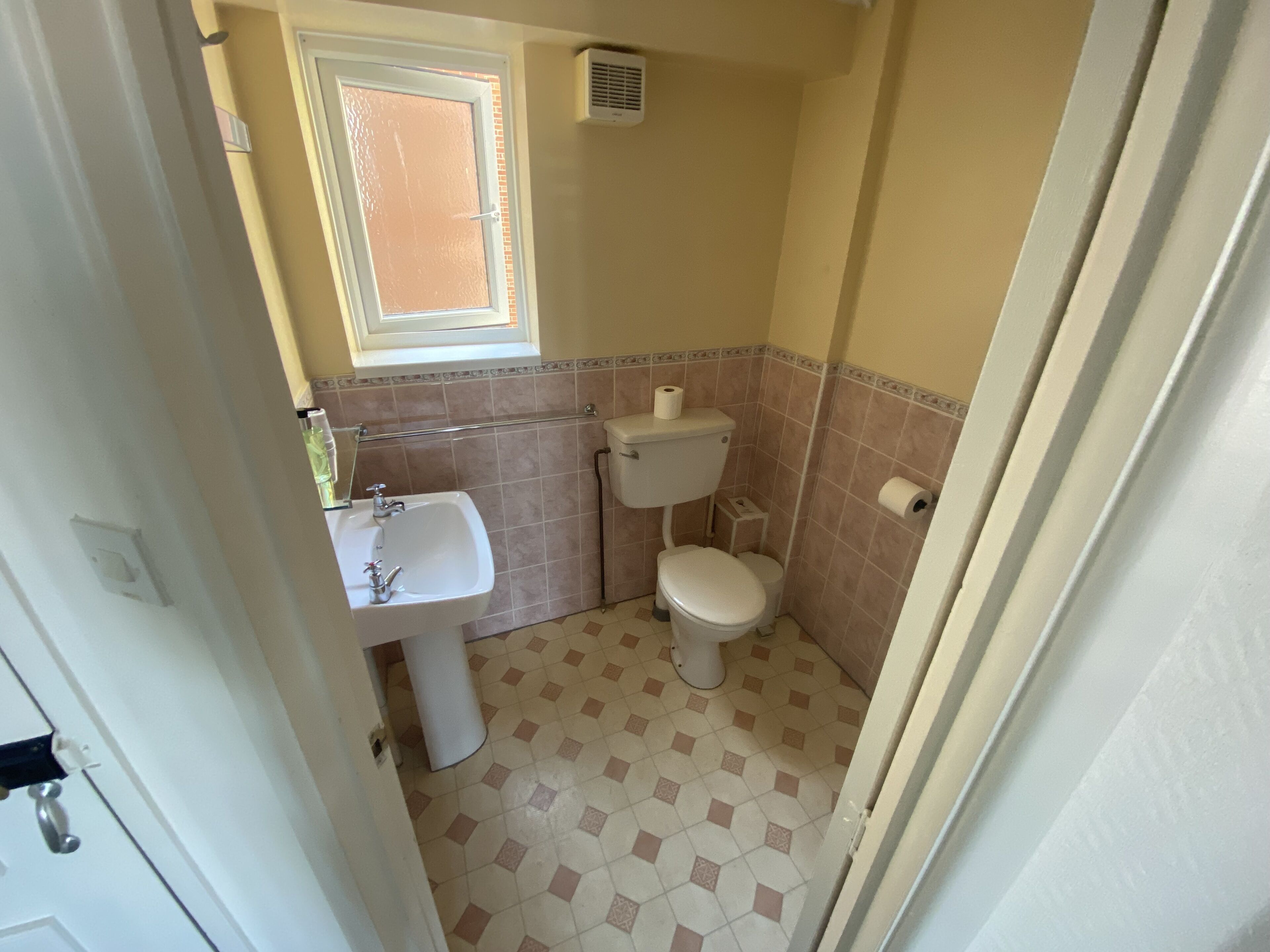 Ein kleines Badezimmer mit Toilette, Waschbecken und Fenster.