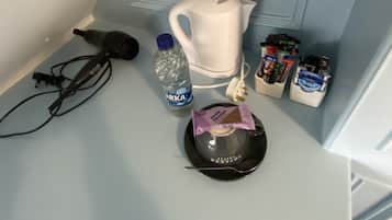Una kitchenette con hervidor, botella de agua, cafetera y condimentos.