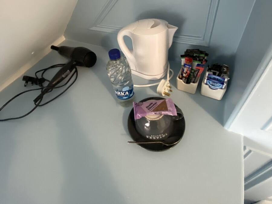 Una kitchenette con hervidor, botella de agua, cafetera y condimentos.