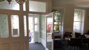 A hotel lobby with a check-in desk, seating area, and large windows. - Fairhaven Hotel (Weymouth)